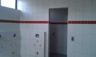 WC Rückwand mit weißen Fliesen und roter Bordüre